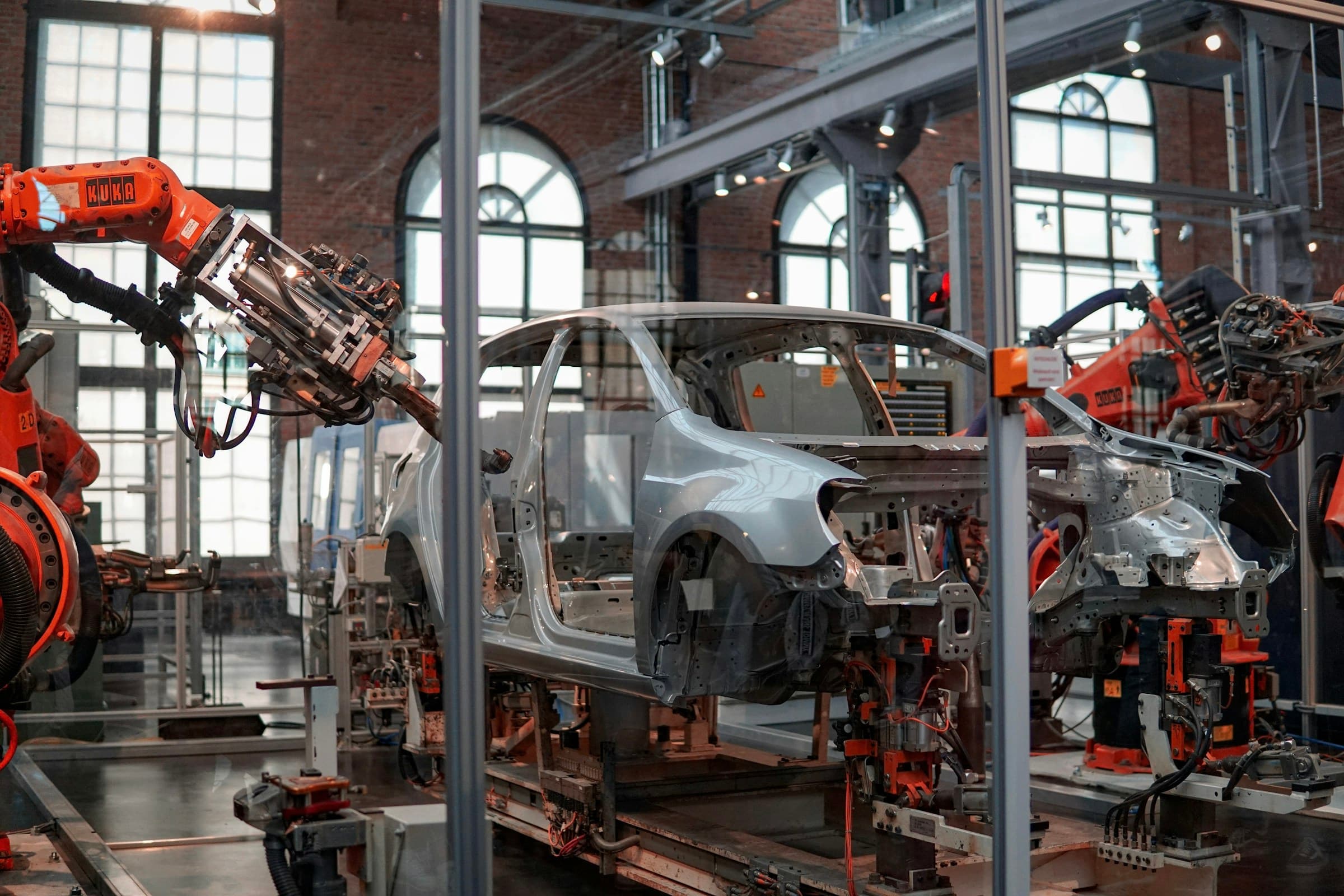 Des bras robotisés assemblant une carrosserie de voiture dans une halle en brique