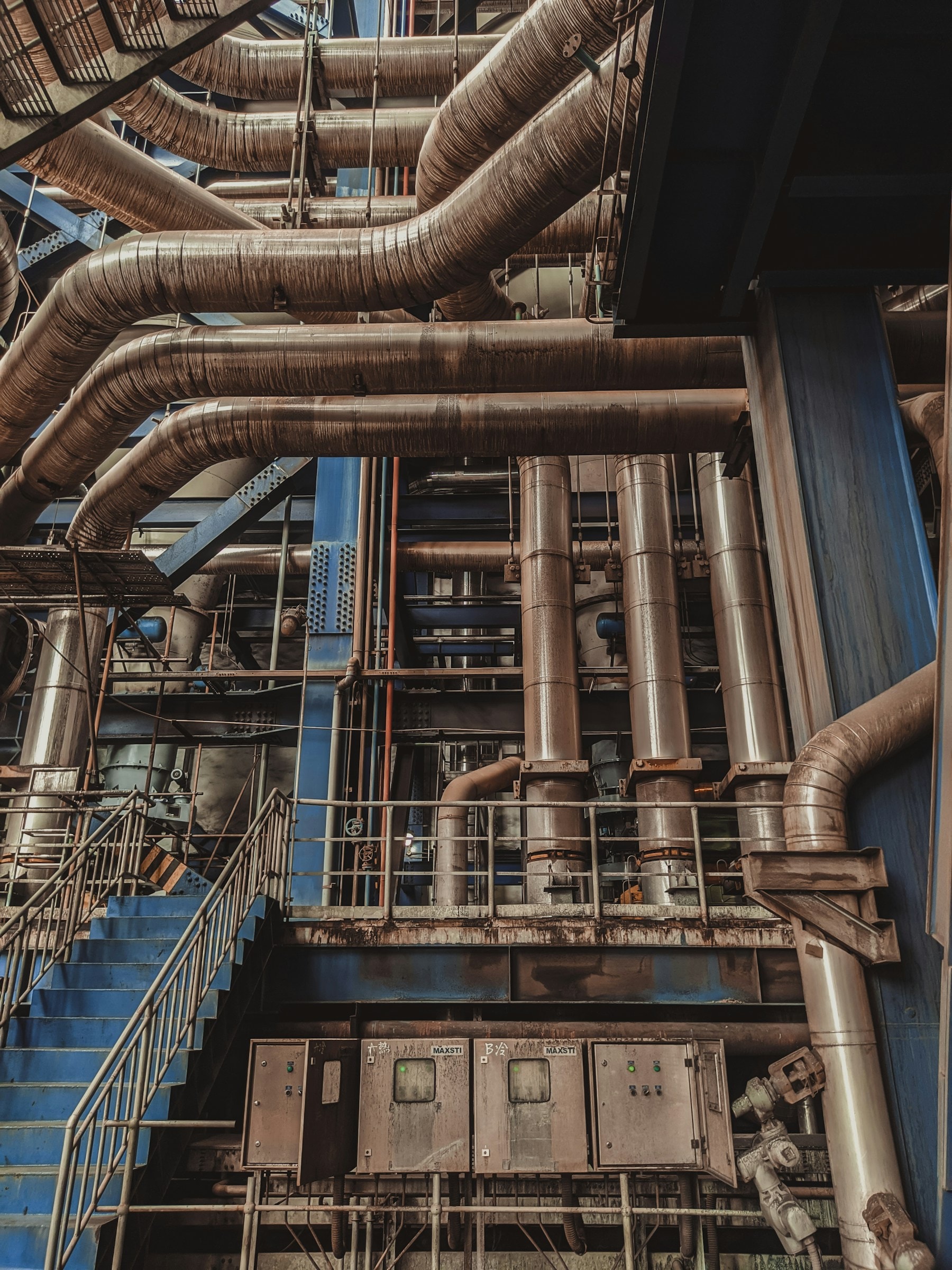 Des tuyauteries, des escaliers et des armoires électriques au cœur d'une usine
